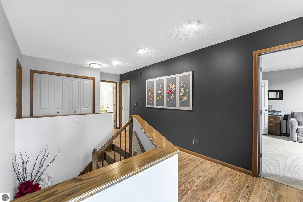 Interior hallway of a luxury home at 5347 Birch Glen Road, featuring wooden staircase, dark accent wall with floral artwork, and doors leading to different rooms, showcasing modern design elements and spacious layout.