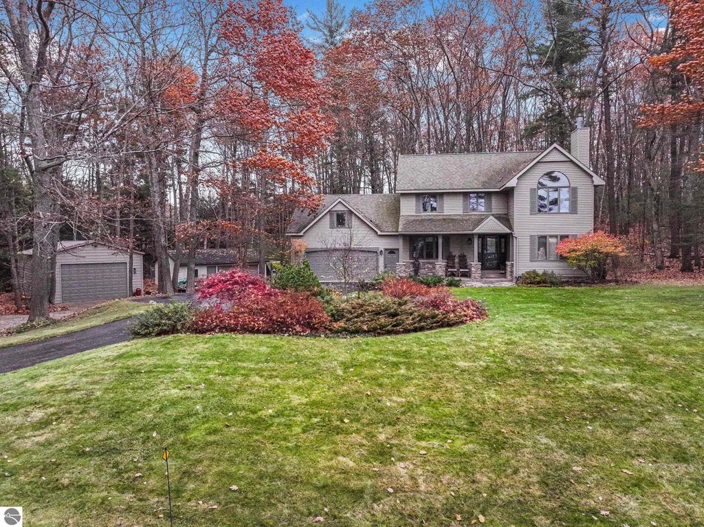 Modern luxury home at 5347 Birch Glen Road, Lake Ann, MI, surrounded by colorful autumn foliage and landscaped yard, featuring a two-car garage and spacious driveway.