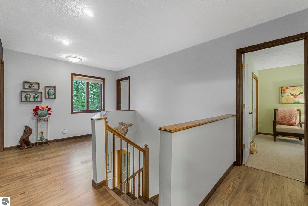 Spacious interior hallway of luxury home at 5347 Birch Glen Road, featuring natural light from large windows, decorative shelves, and wooden staircase, reflecting modern design in Lake Ann, MI.