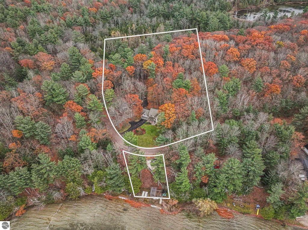 Aerial view of 5347 Birch Glen Road, Lake Ann, MI, showcasing a wooded property with vibrant autumn foliage, highlighted boundaries for two parcels, and proximity to Lake Ann, emphasizing the blend of lakefront living and spacious acreage.