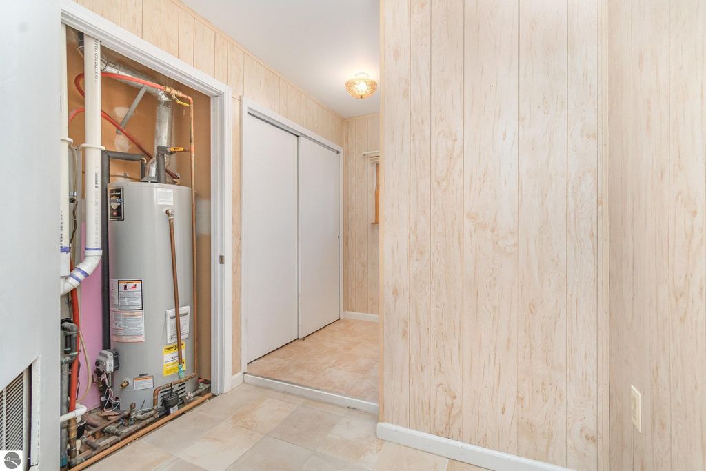 Mudroom entry of a 2-bedroom home featuring a water heater, closet doors, and light-colored wood paneling, highlighting functionality and space in a Mt Pleasant, MI property listing.