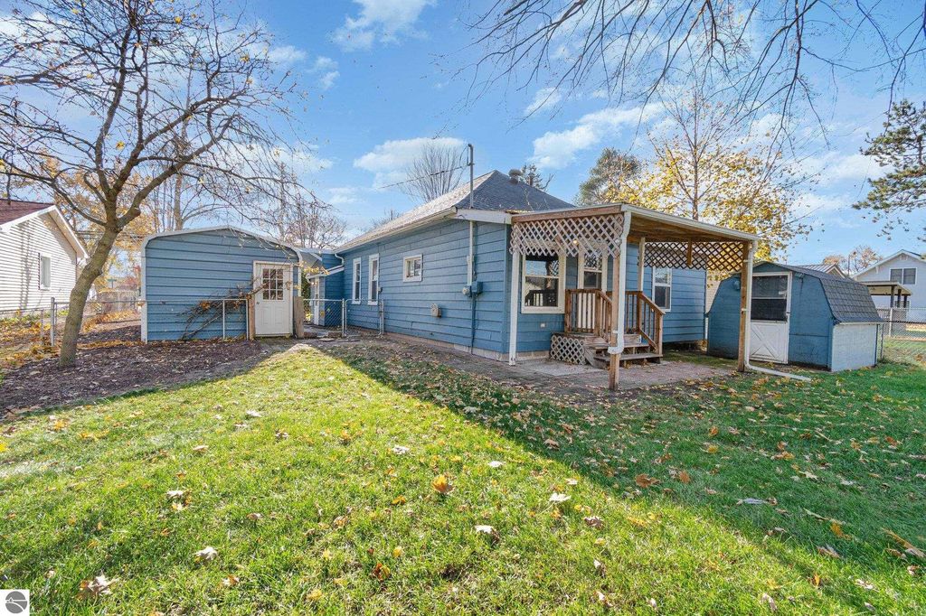 Exterior view of a blue single-family home with a mudroom entry, fenced yard, and adjacent garage, located at 1435 E Broadway Street, Mt Pleasant, MI.