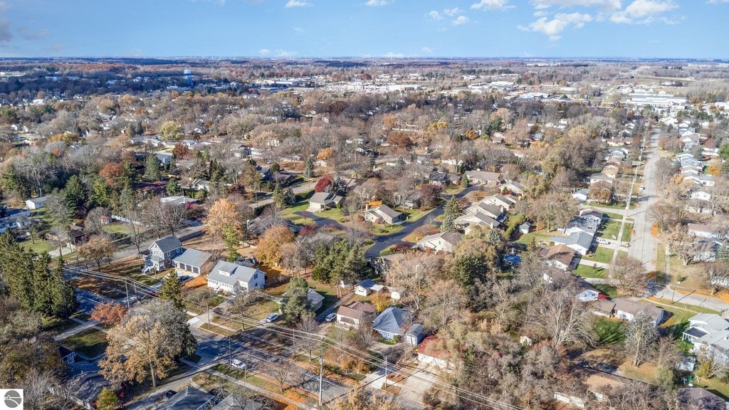 Aerial view of residential neighborhood in Mt Pleasant, MI, showcasing tree-lined streets, single-family homes, and autumn foliage, highlighting the community's proximity to local amenities.