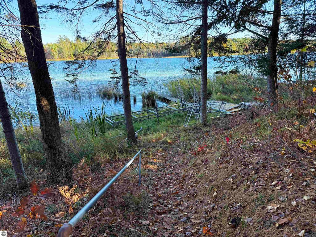 Scenic view of Pickerel Lake from wooded area, featuring a dock and lush shoreline, highlighting potential for waterfront activities and serene setting for building a home.