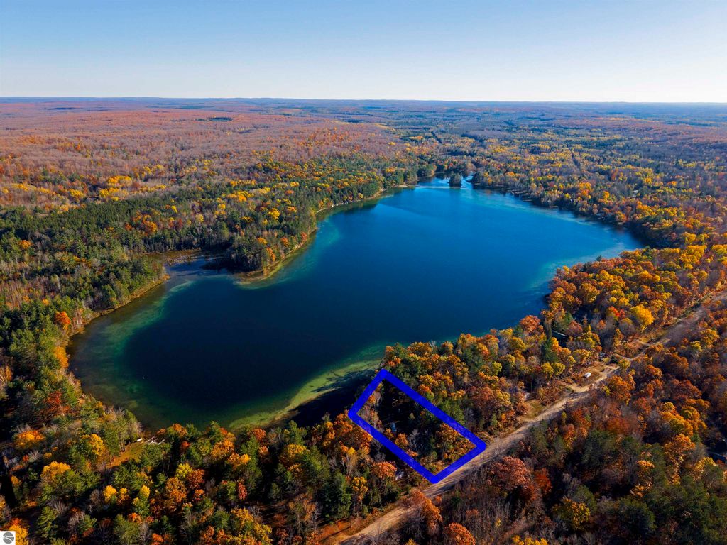 Aerial view of Pickerel Lake in Kalkaska, MI, showcasing vibrant autumn foliage, with a highlighted parcel of land suitable for building a home or getaway, featuring lake access and wooded surroundings.