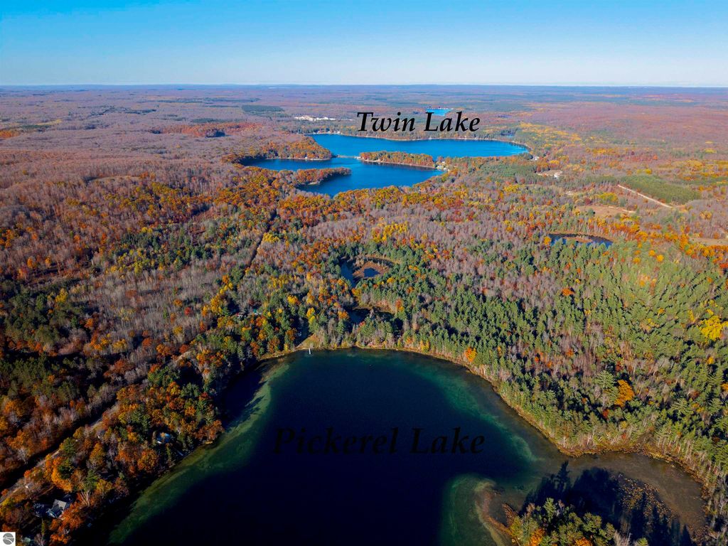 Aerial view of Pickerel Lake and Twin Lake surrounded by vibrant autumn foliage, showcasing the scenic landscape ideal for building a dream home or getaway near Kalkaska, MI.