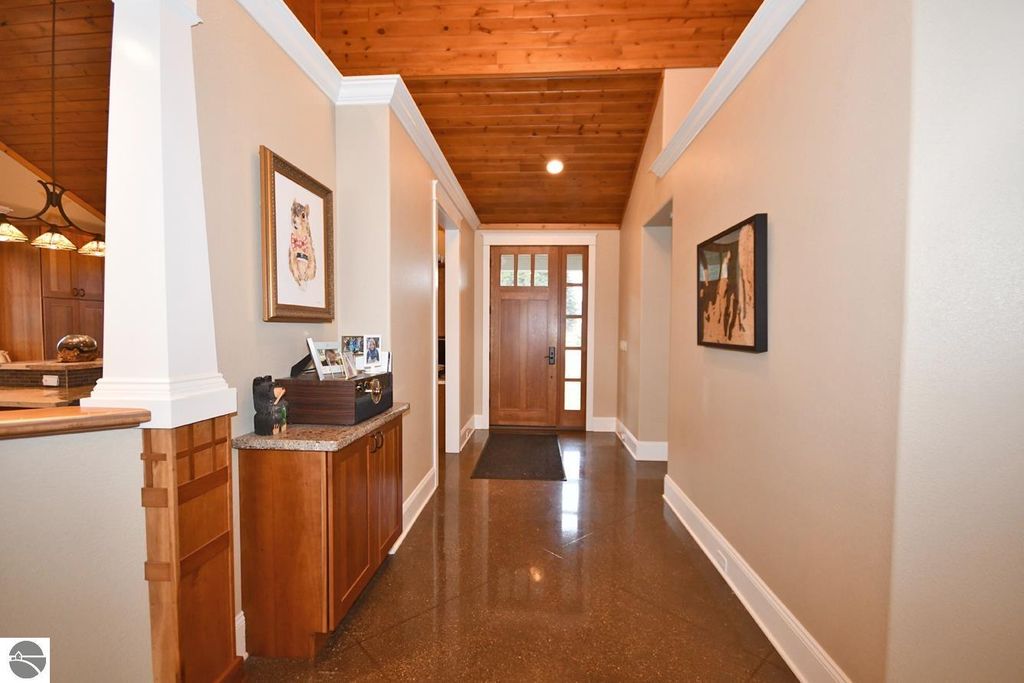 Welcoming entryway of a luxury home featuring polished concrete floors, wooden accents, and a view of the front door, highlighting the open layout and craftsmanship of the property at 11007 S Rolling Meadows Drive, Maple City, MI.