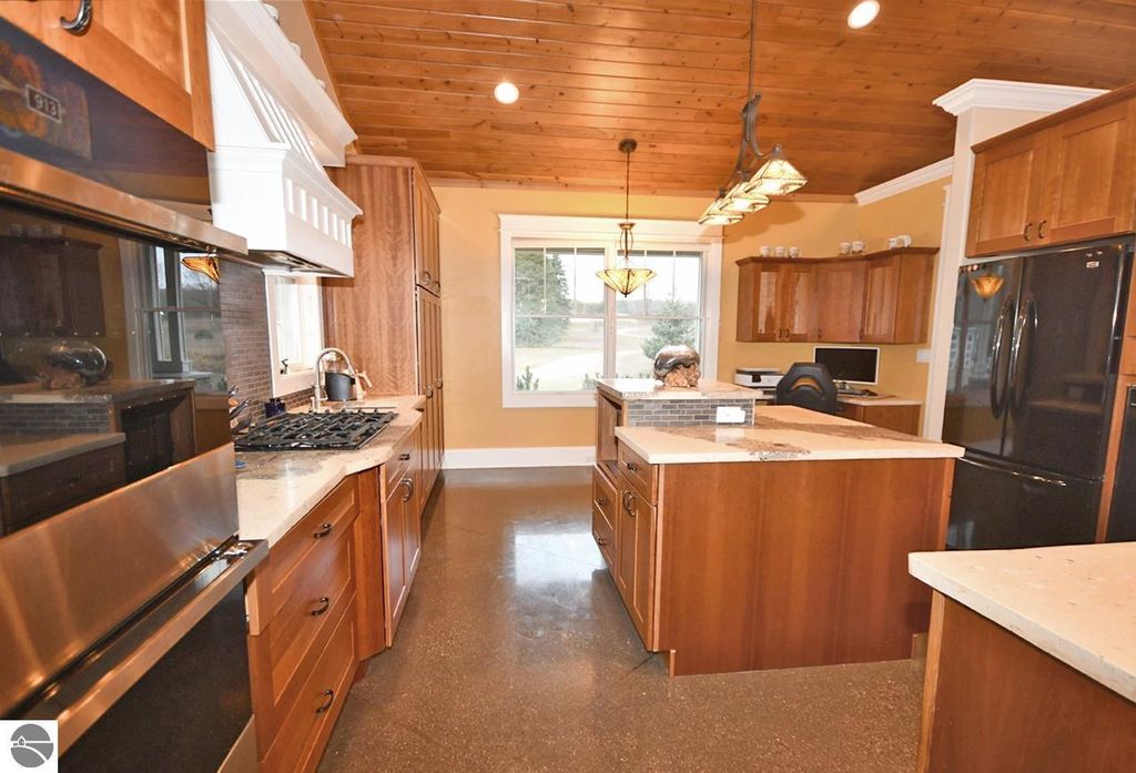 Modern kitchen featuring wooden cabinetry, granite countertops, stainless steel appliances, and a spacious island with seating, showcasing a bright and inviting atmosphere.