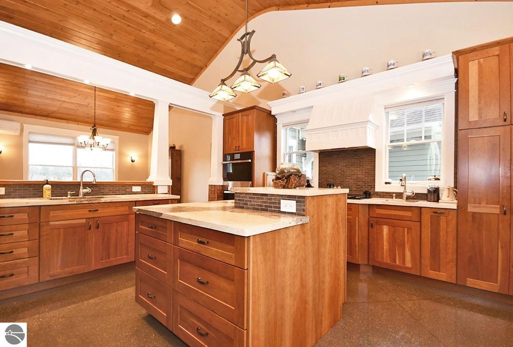 Spacious kitchen with wooden cabinetry, stone countertops, and vaulted ceiling, showcasing an open layout ideal for entertaining in the Maple City home at 11007 S Rolling Meadows Drive.