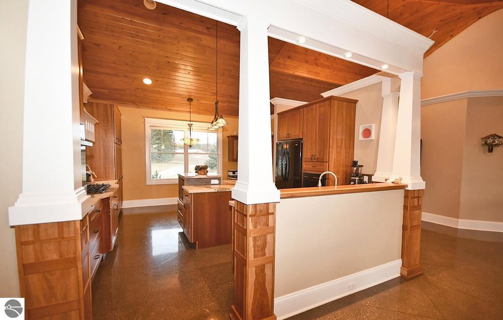 Kitchen interior with wood cabinetry, granite countertops, and vaulted ceiling, showcasing an open layout ideal for entertaining in the Maple City, MI property listing.