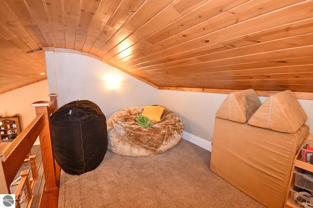 Cozy loft space featuring two bean bag chairs and a triangular pillow against a wooden ceiling, highlighting the home's inviting atmosphere at 11007 S Rolling Meadows Drive, Maple City, MI.