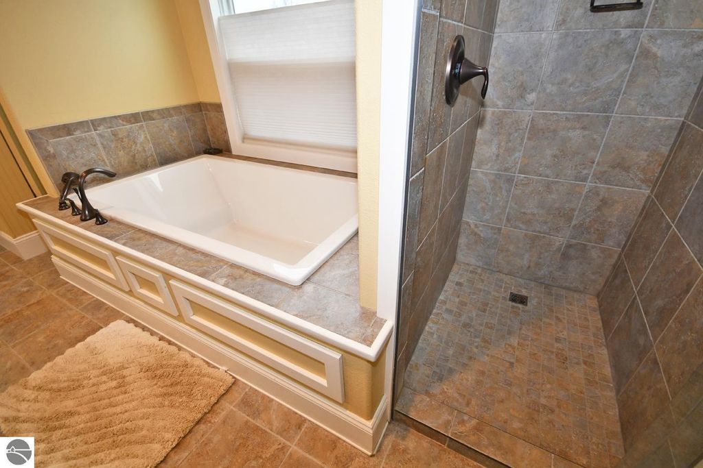 Luxurious bathroom with a soaking tub and separate tiled shower, featuring modern fixtures and natural light.