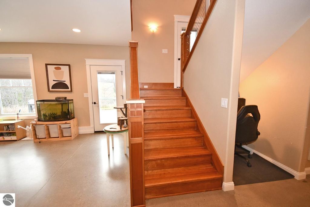 Interior view of a modern home entryway featuring wooden stairs, a fish tank, and a workspace, showcasing the open floor plan and natural light, relevant to the Maple City property listing.