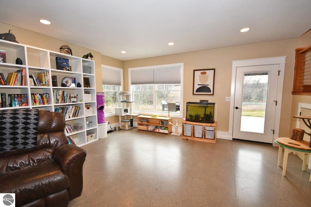 Cozy living space in a Maple City home featuring a bookshelf, leather recliner, large windows, and an aquarium, showcasing a blend of comfort and natural light.