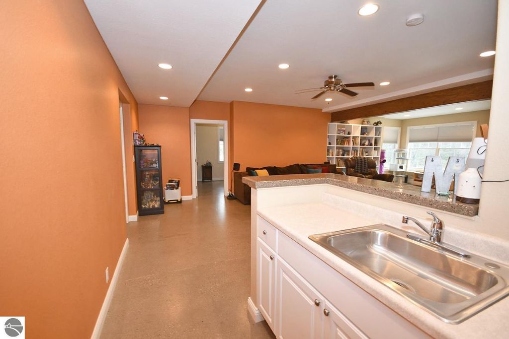Interior view of the kitchen and living area at 11007 S Rolling Meadows Drive, featuring an open layout, orange walls, modern fixtures, and a view into the living space with a cozy couch and shelving.