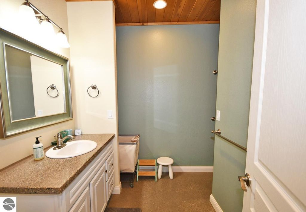 Modern bathroom with a vanity, large mirror, and walk-in shower, featuring natural wood accents and a neutral color palette, reflecting the home's craftsmanship and design.