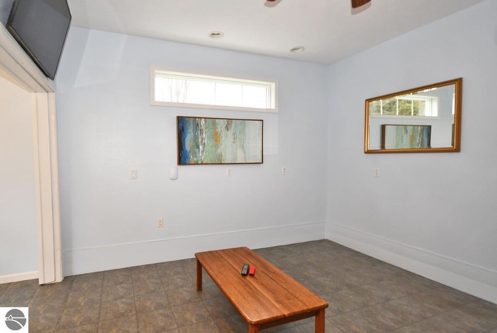 Spacious interior of a guest house featuring light blue walls, a wooden table, and decorative paintings, highlighting the inviting atmosphere of the property at 11007 S Rolling Meadows Drive, Maple City, MI.