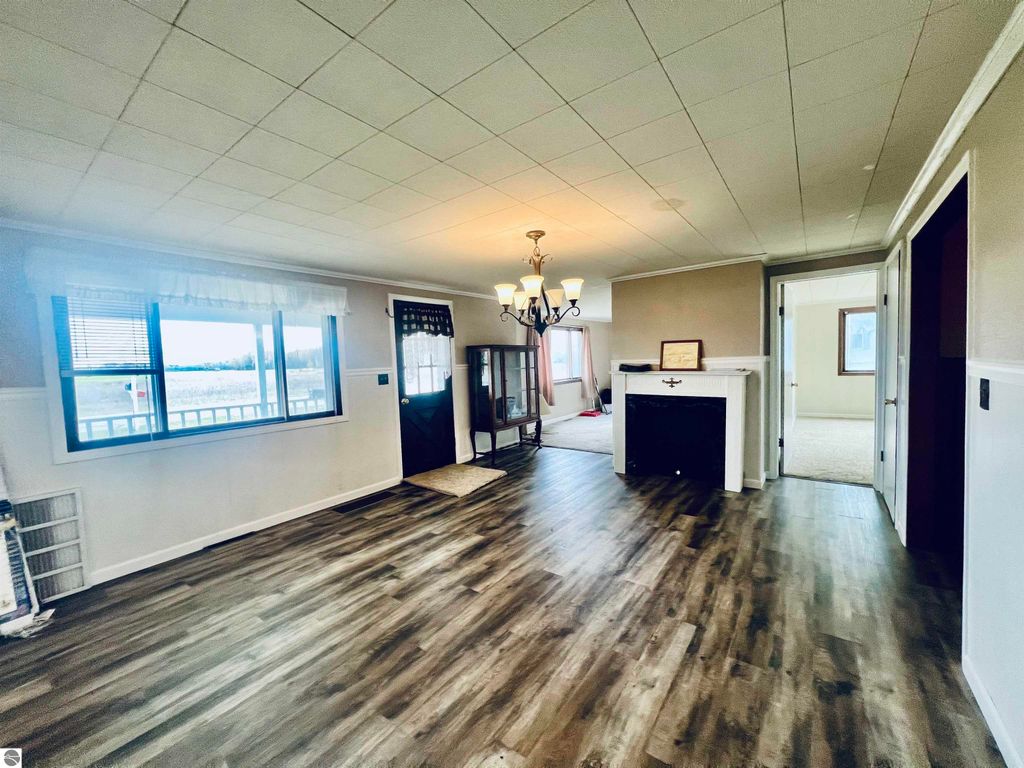 Spacious living room of a three-bedroom home at 889 N Ferris Road, featuring a chandelier, large window with scenic views, and a fireplace, showcasing a blend of warmth and functionality.