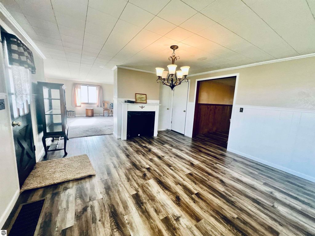 Interior view of the entryway at 889 N Ferris Road, featuring a chandelier, hardwood flooring, and a decorative fireplace, leading to a spacious living area with large windows.
