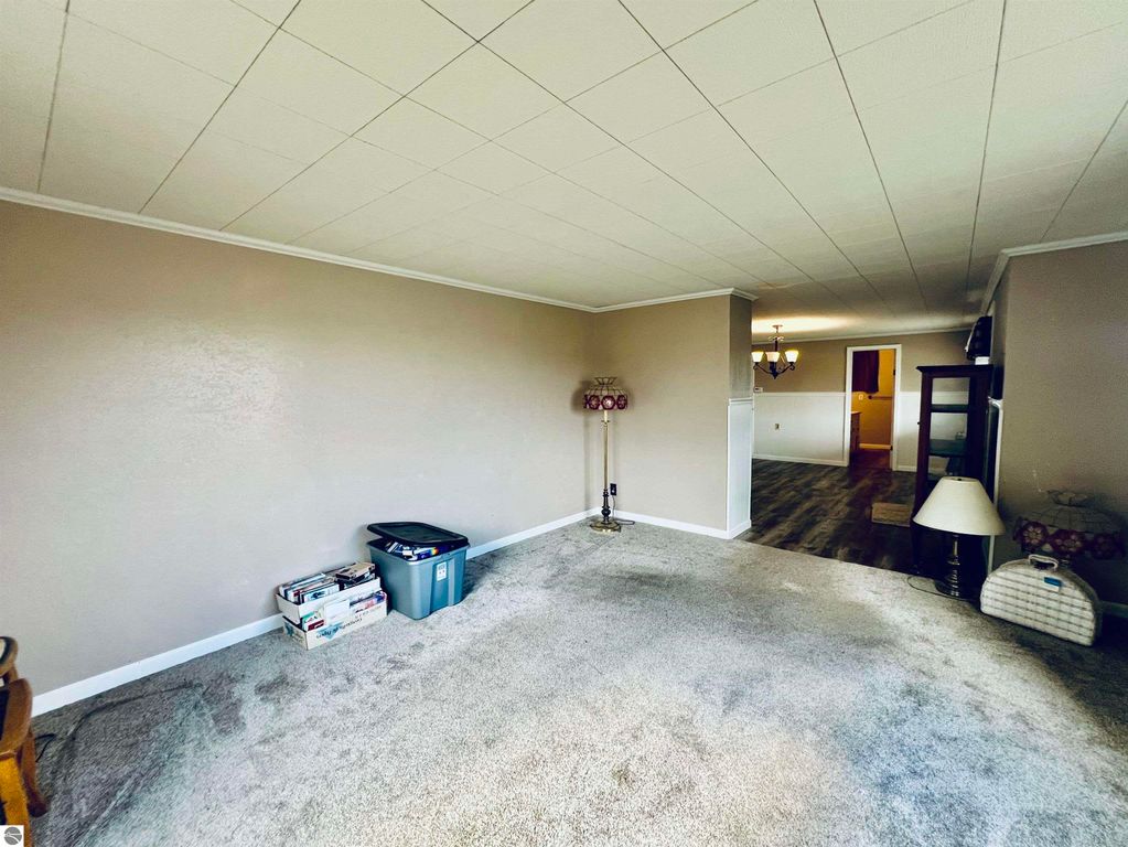Living room interior of a three-bedroom home at 889 N Ferris Road, featuring beige walls, carpeted floor, a lamp, and a decorative chair, showcasing a spacious layout ideal for family gatherings.