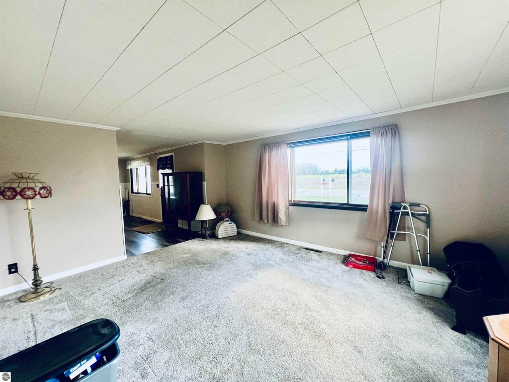 Spacious living room of a three-bedroom home at 889 N Ferris Road, featuring large window with natural light, carpeted flooring, and cozy decor elements.