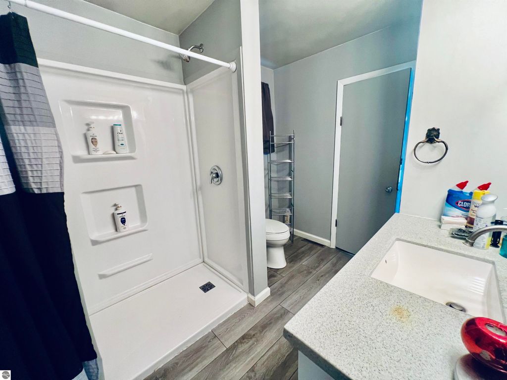 Bathroom interior featuring a shower stall, sink with countertop, and modern decor, highlighting the home's functional spaces at 889 N Ferris Road, Sumner, MI.