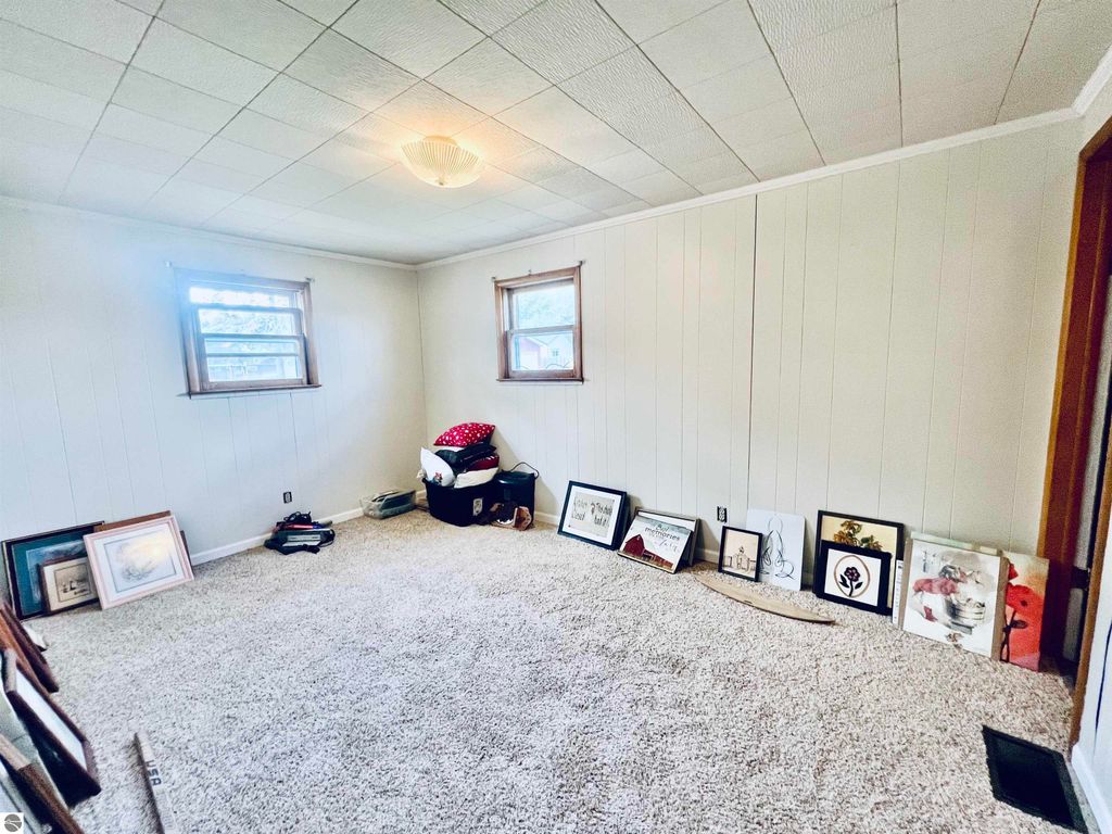 Spacious interior of a three-bedroom home at 889 N Ferris Road, featuring light-colored walls, two windows, and a collection of framed artwork along the floor, showcasing the potential for personalization in a well-maintained living space.