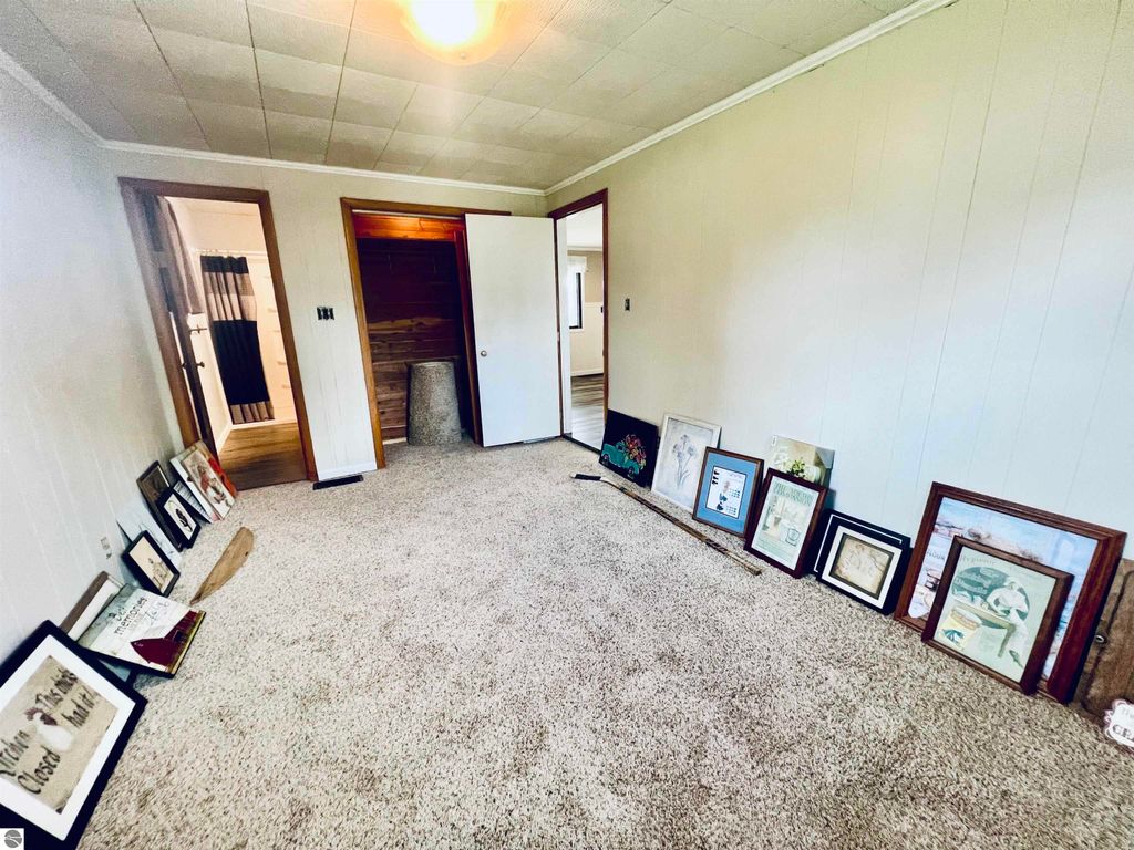 Interior view of a cozy room at 889 N Ferris Road, featuring beige walls, plush carpet, and framed artwork leaning against the wall, showcasing the home's warm and inviting atmosphere.