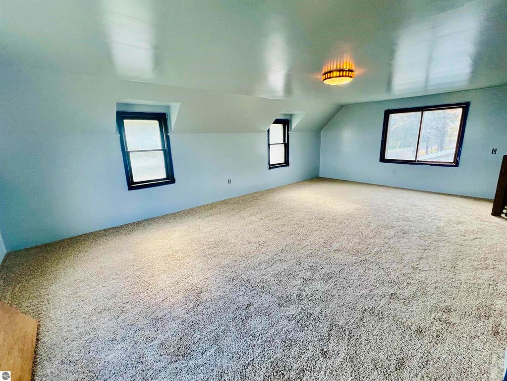 Spacious carpeted interior of a three-bedroom home with large windows and modern lighting, showcasing the living area at 889 N Ferris Road, Sumner, MI.