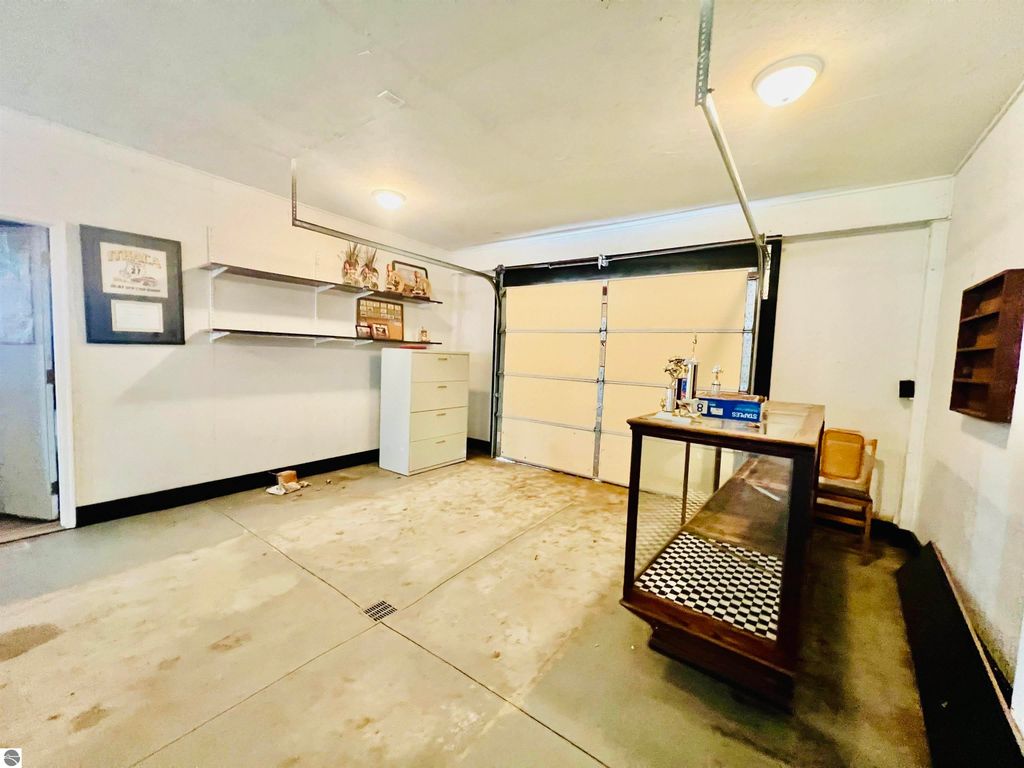 Spacious garage interior featuring concrete floors, shelves, and a workbench, highlighting ample storage and workspace for vehicles and projects at 889 N Ferris Road, Sumner, MI.