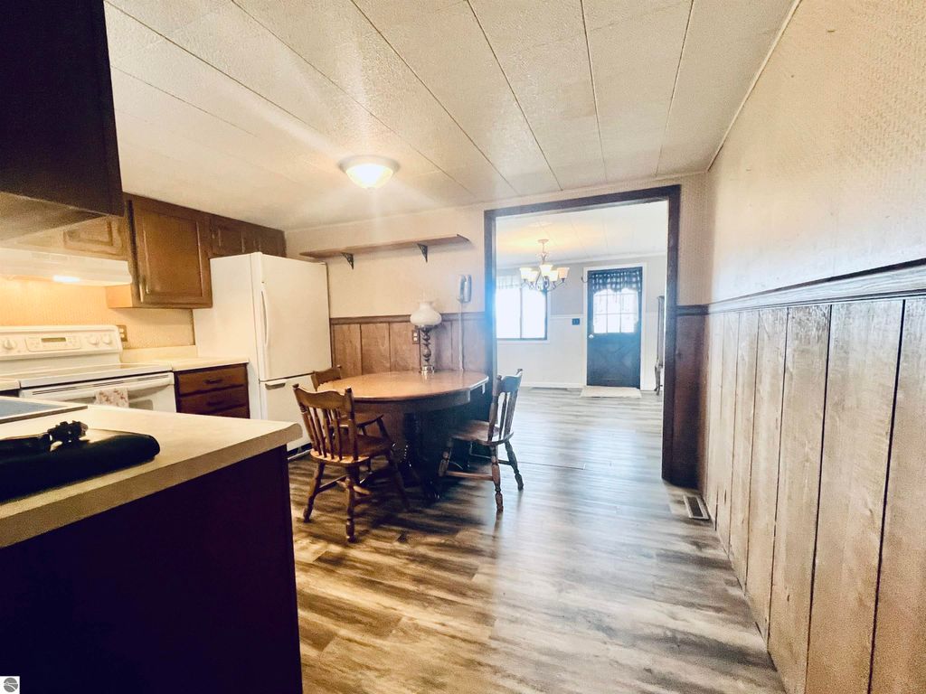 Cozy kitchen area with wooden cabinetry, dining table, and white appliances, showcasing the inviting interior of a three-bedroom home at 889 N Ferris Road, Sumner, MI.