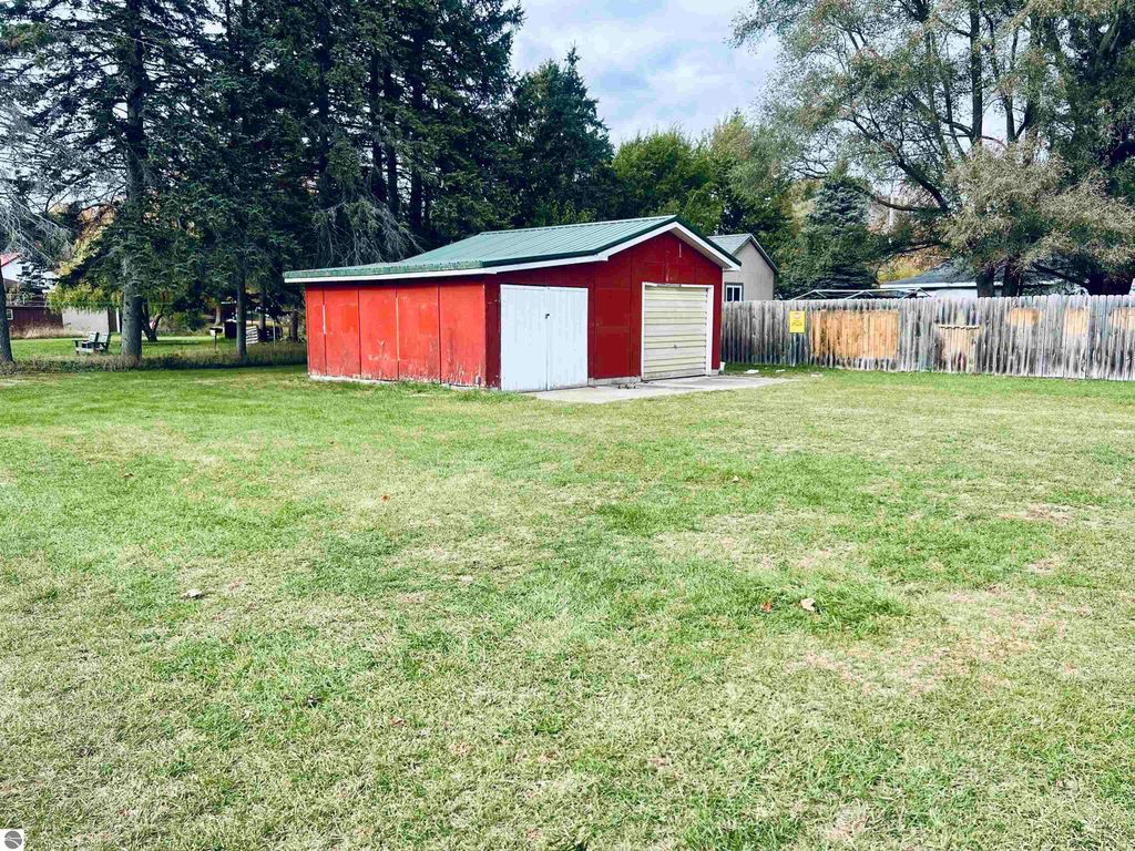 Red barn-style garage with white doors on a spacious corner lot at 889 N Ferris Road, surrounded by green grass and trees, showcasing ample outdoor space for vehicles and projects.