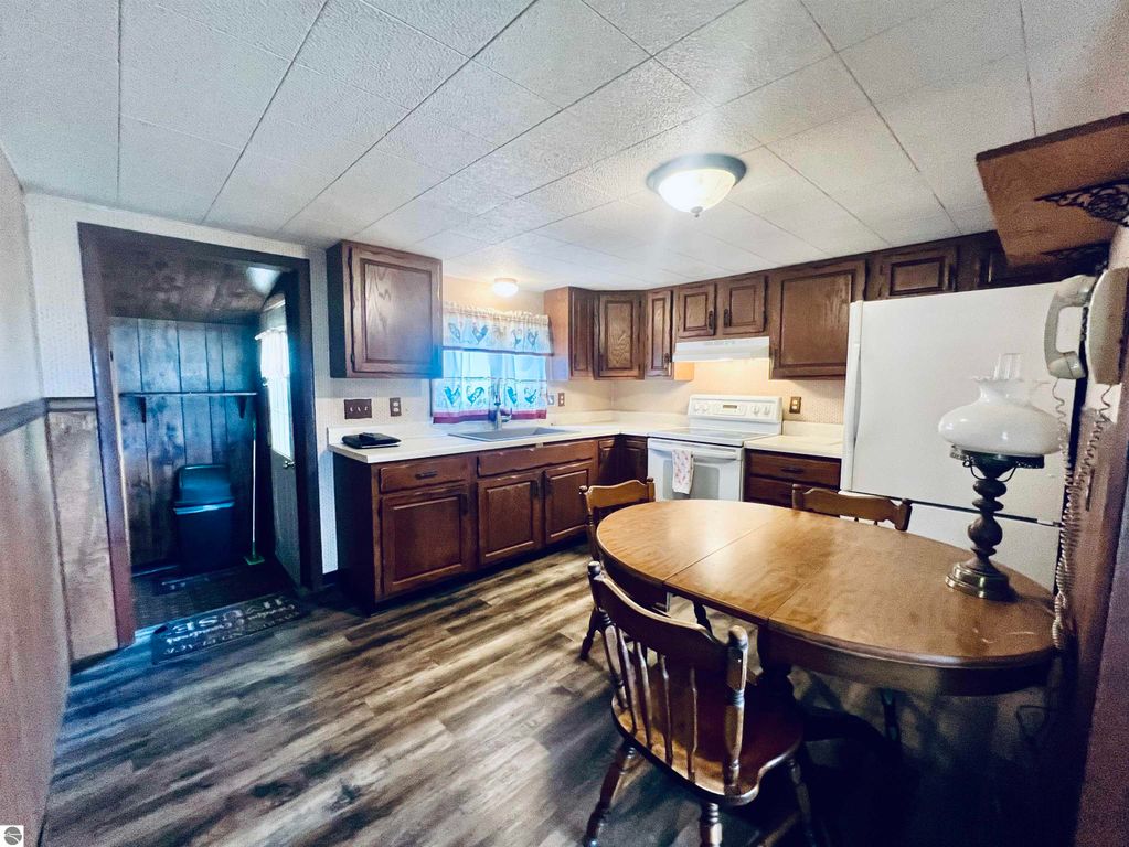 Cozy kitchen interior featuring wooden cabinetry, a round dining table with chairs, and a view of the adjacent room, highlighting the charm of the home at 889 N Ferris Road, Sumner, MI.
