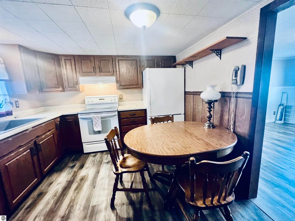 Cozy kitchen with wooden cabinets, white appliances, and a round dining table, showcasing a warm, inviting space in the home at 889 N Ferris Road, Sumner, MI.