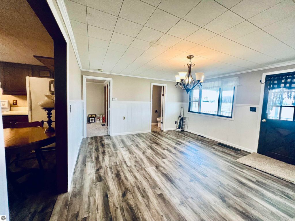 Spacious interior of a three-bedroom home at 889 N Ferris Road, featuring a chandelier, large windows, and open layout with new flooring, highlighting charm and functionality.