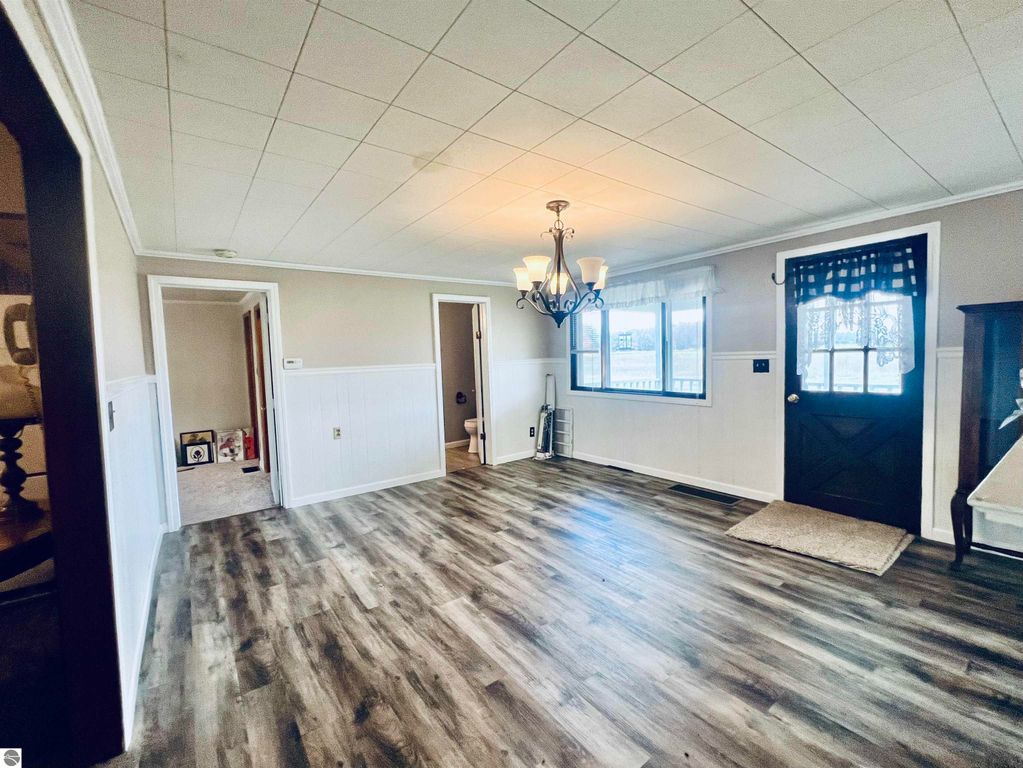 Interior view of a charming home at 889 N Ferris Road, featuring a spacious living area with modern laminate flooring, a chandelier, large windows, and a decorative door, reflecting warmth and inviting atmosphere.