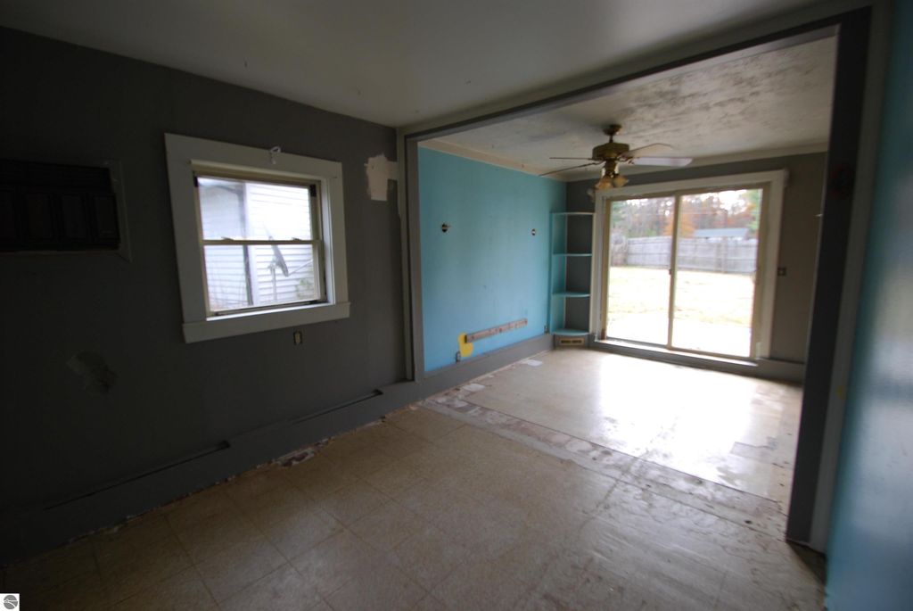 Interior view of a fixer-upper home at 1532 Rabbit Track Drive, featuring a partially finished room with a ceiling fan, large sliding glass door leading to the backyard, and a window, highlighting the property's potential for renovation.