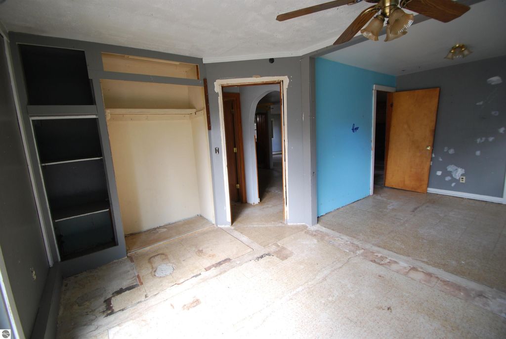 Interior view of a fixer-upper home at 1532 Rabbit Track Drive, featuring a corner room with shelves, a closet, and a blue accent wall, showcasing potential for renovation.