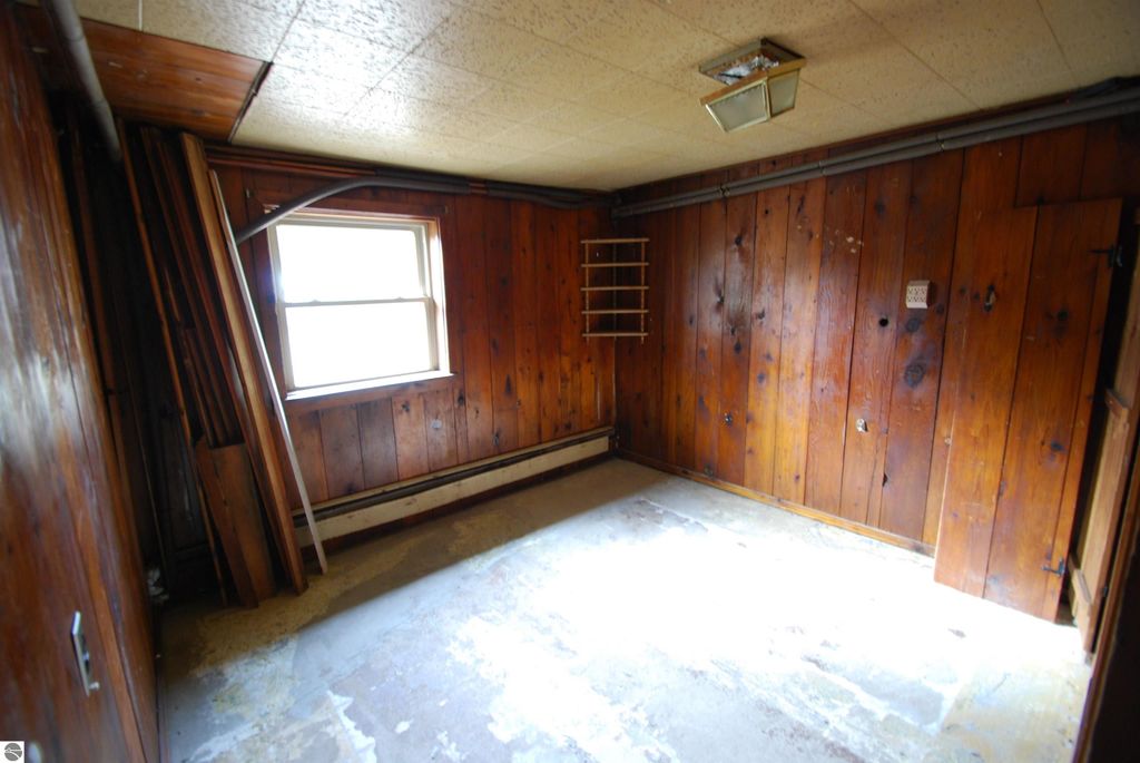 Interior view of a fixer-upper home at 1532 Rabbit Track Drive, featuring wooden paneling, a window, and stacked lumber, highlighting potential for renovation.
