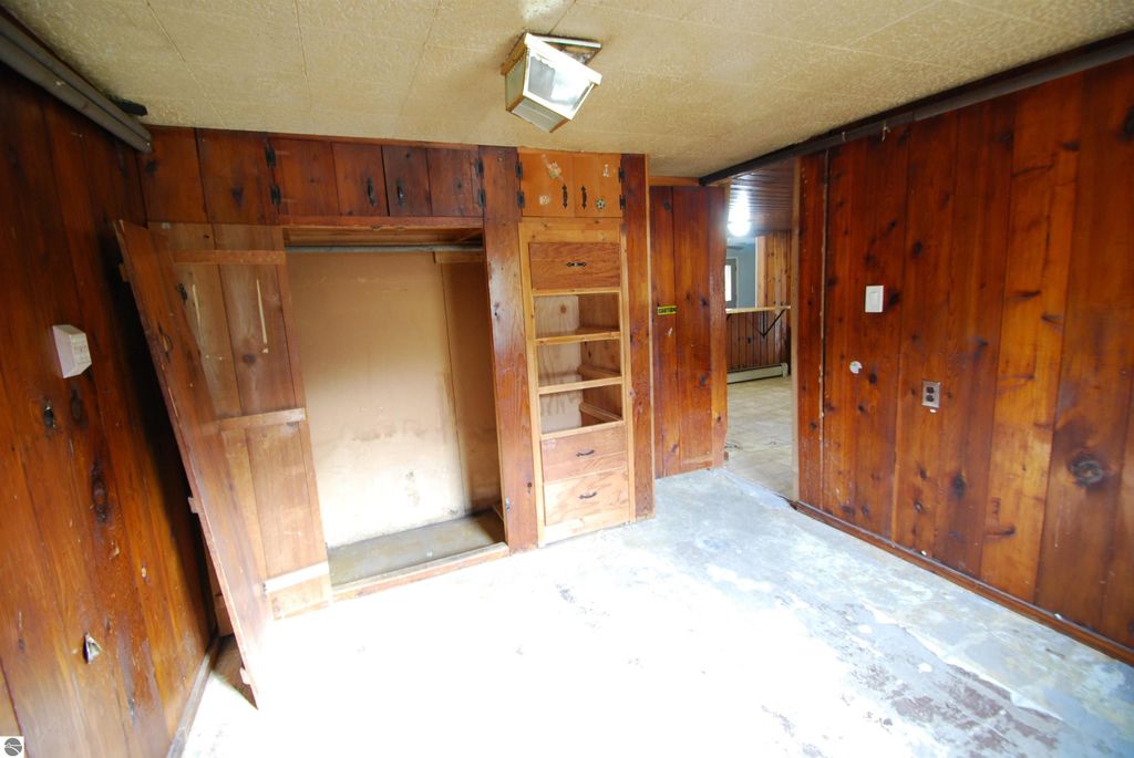 Interior view of a fixer-upper home at 1532 Rabbit Track Drive, featuring wooden paneling, built-in shelves, and an open closet space, highlighting potential for renovation.