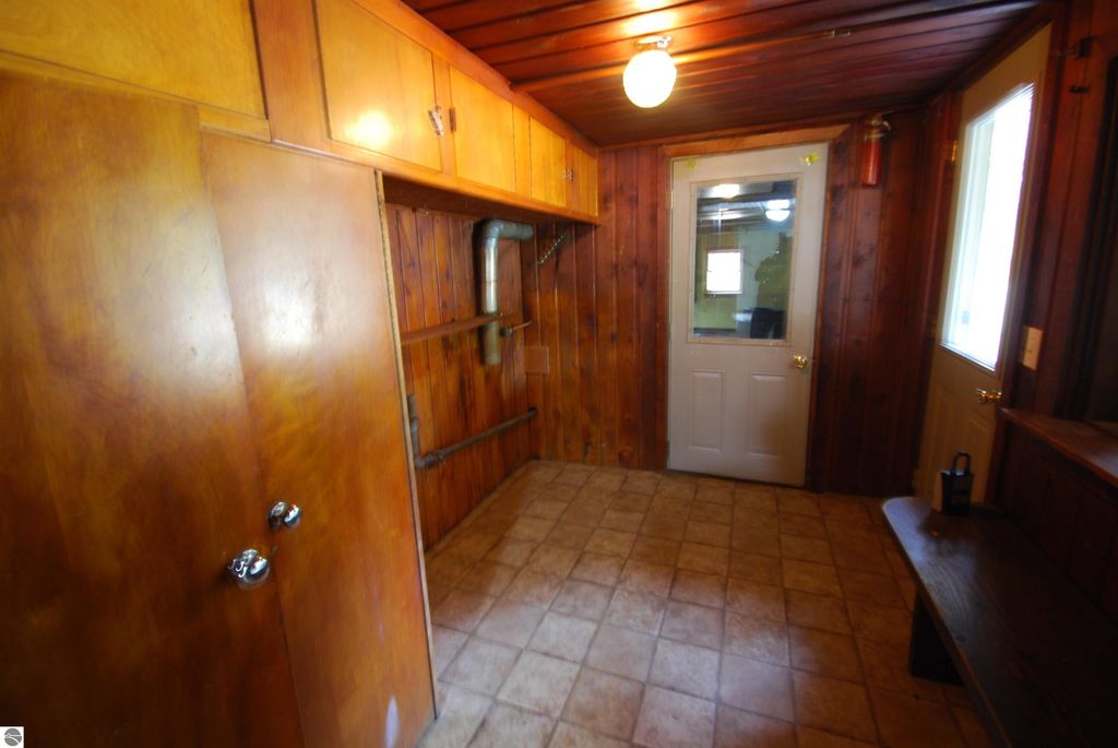 Interior view of the mudroom in a fixer-upper home at 1532 Rabbit Track Drive, featuring wood paneling, tile flooring, and a door leading outside.