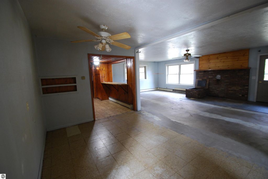 Interior view of a fixer-upper home at 1532 Rabbit Track Drive, featuring a spacious living area with ceiling fan, exposed brick fireplace, and potential for remodeling.