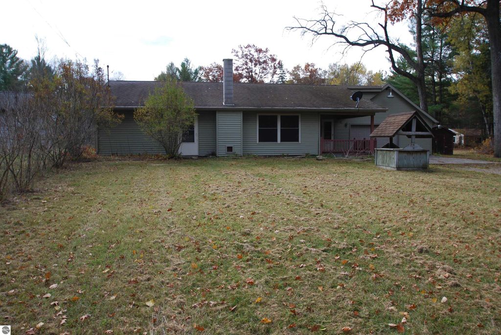 Three-bedroom fixer-upper home at 1532 Rabbit Track Drive, Alger, MI, featuring a spacious yard, attached two-car garage, and garden shed, set on a corner double lot.