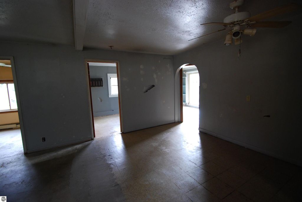 Interior view of fixer-upper home at 1532 Rabbit Track Drive, Alger, MI, featuring spacious rooms, ceiling fan, and light-colored walls, showcasing potential for renovation.