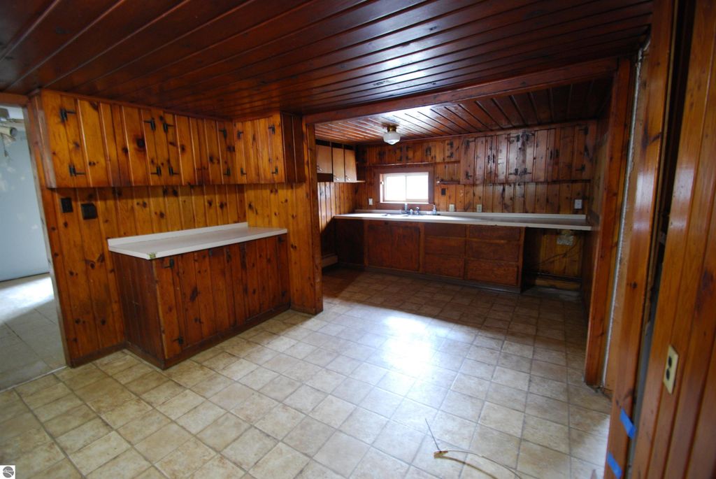 Interior view of a fixer-upper kitchen with wooden cabinets and countertops, showcasing potential for renovation, located in the property listing at 1532 Rabbit Track Drive, Alger, MI.