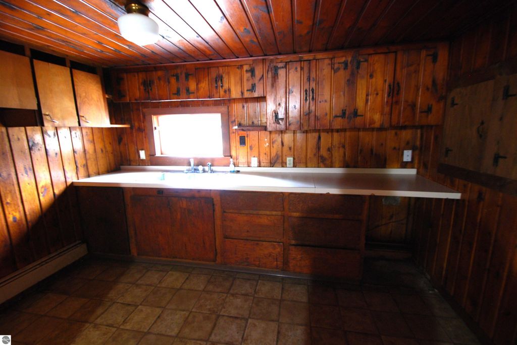 Kitchen interior with wooden cabinets and countertops, featuring a window above the sink, part of a fixer-upper property at 1532 Rabbit Track Drive, Alger, MI.