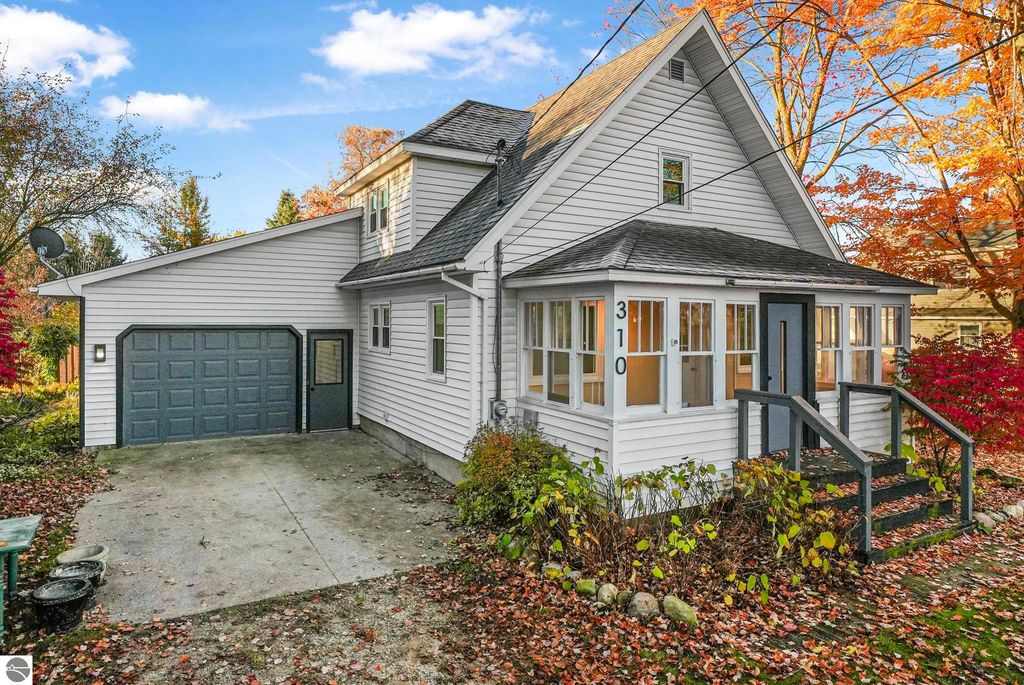 Updated two-story home at 310 E Euclid Street, McBain, MI, featuring a garage, welcoming entryway, and surrounded by autumn foliage.