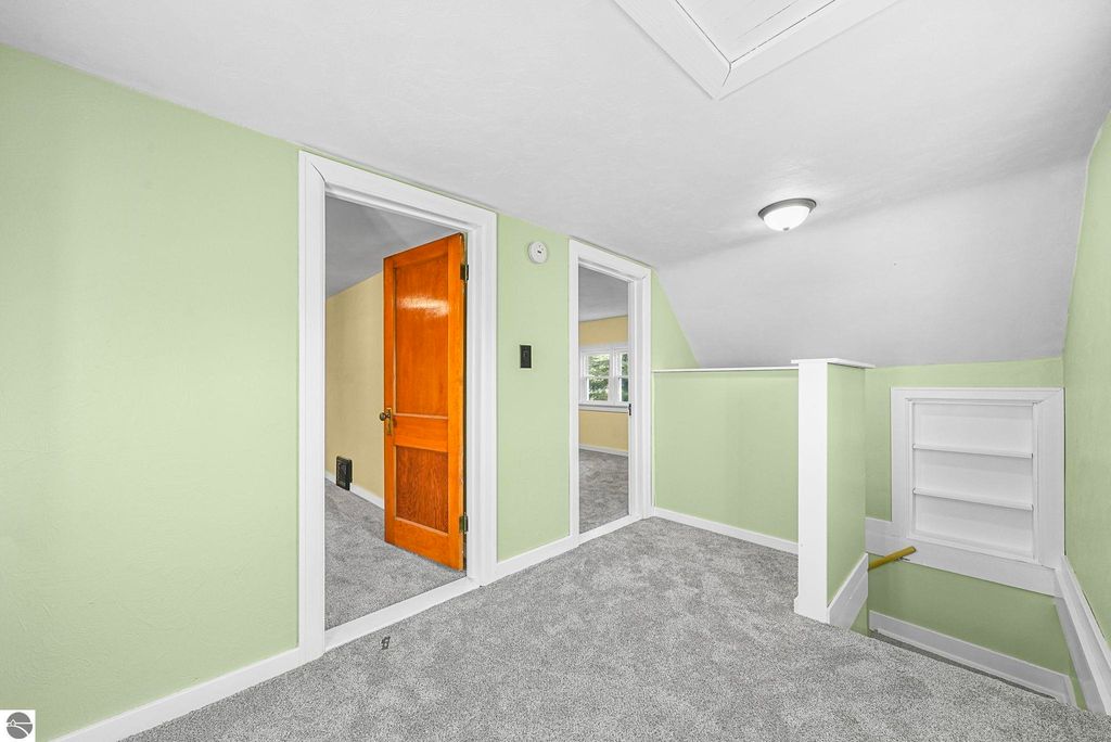 Spacious upstairs landing with light green walls, plush carpeting, and wooden doors leading to adjacent rooms, showcasing modern updates in a McBain home.