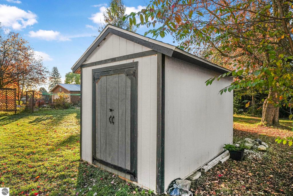 Backyard garden shed surrounded by greenery and trees, showcasing storage space in the property at 310 E Euclid Street, McBain, MI.