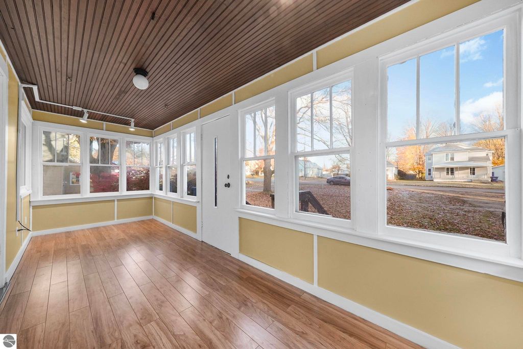 Bright sunroom with large windows, wooden ceiling, and modern flooring, showcasing the inviting entryway of the updated 3-bedroom home at 310 E Euclid Street, McBain, MI.